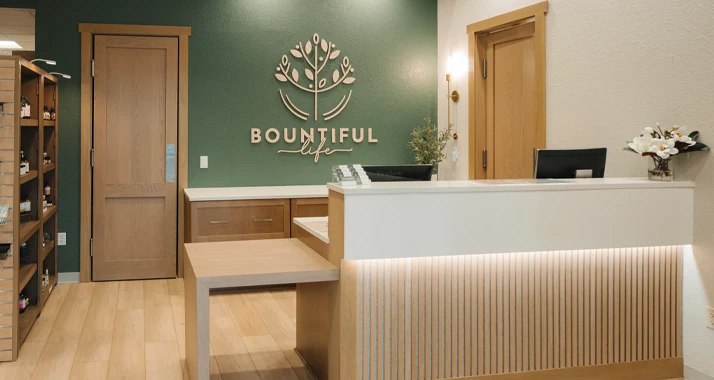 Modern reception area with clean wood accents, green feature wall, and organized front-desk workspace